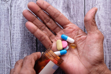 Elderly woman pouring pills from bottle on hand with copy space 