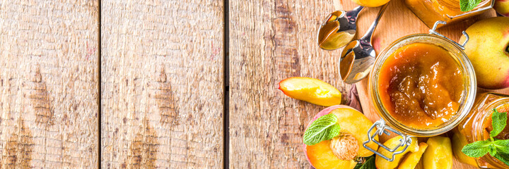 Homemade peach jam in different jars, with fresh organic peaches on wooden rustic background copy...