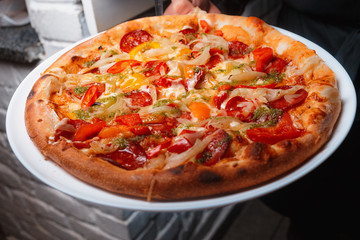 Tasty Italian pizza with cheese, pepperoni, arugula, cocktail tomatoes and  grilled bell pepper