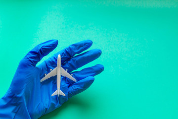 Flight resumption after Coronavirus epidemic. A hand in a blue protective glove holds a plane