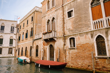 Fototapeta na wymiar Canals in Venice, Italy. Boats moored in front of the houses, narrow canal in Venice, Italy during the day with historical buildings