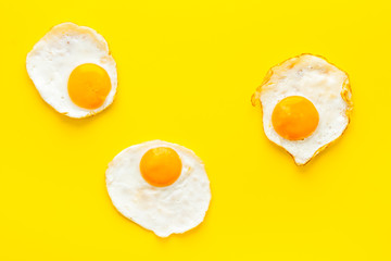 Fried eggs on yellow background top view