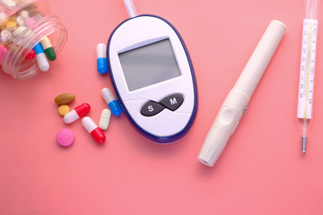  blood sugar measurement kits, pills and thermometer on pink 