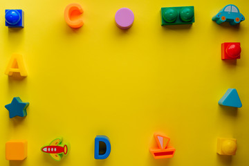 Top view on children s toys on a yellow background. Children's toys on the table. concept for advertising toys for children. Copy space children's toy.
