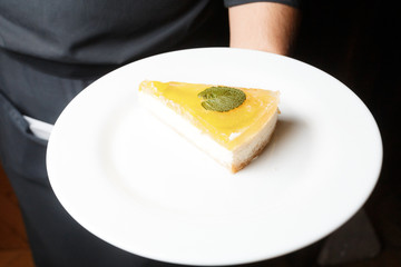 Classic cheesecake with yellow jelly topping served on white plate