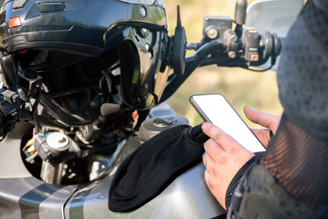Motor biker is showing in hands a blank screen mobile phone. Online navigator.