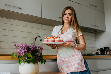 The action of making red velvet cupcakes. Woman hand adding sugar sprinkle on cupcake.