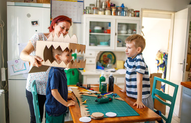 Mom and kids making a cardboard dinosaur costume 
