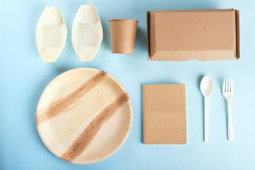 Eco friendly disposable tableware flat lay on light blue background. View from above. 