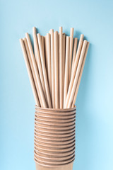 Eco cups with drinking straws on light grey background. Selective focus. Flat lay, view from above.