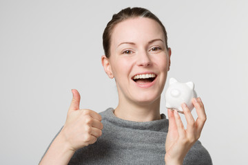 Woman with a piggy bank shows thumbs up