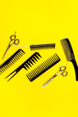 Combs, hairbrush, scissors on yellow desk from above copy space