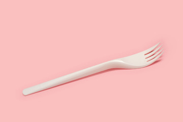 Tenedor de plástico blanco desechable sobre fondo rosa liso y aislado. Vista superior y de cerca. Copy space