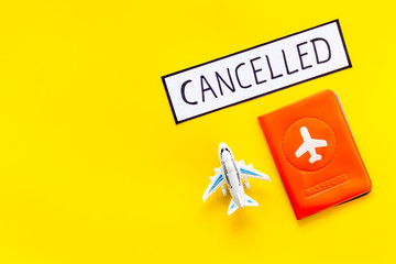 Cancelled flight. Airplane and passport on yellow background top view copy space
