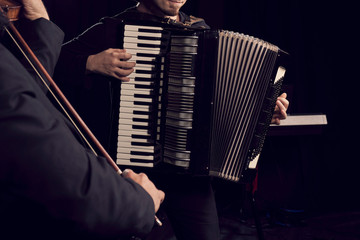 Detail of hands playing an accordion instrument and a violin