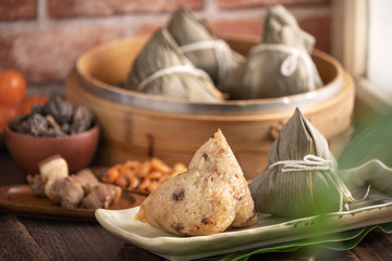 Zongzi - Chinese rice dumpling zongzi in a steamer on wooden table with red brick, window background at home for Dragon Boat Festival concept, close up.
