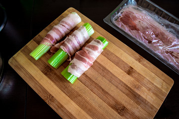 Celery wrapped in bacon on a wooden kitchen Board