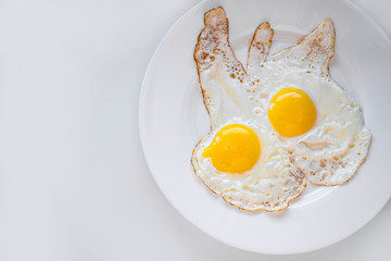 Two eggs fried on a white plate