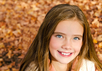 Autumn portrait of adorable smiling little girl child preteen in the park