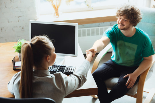 Young man sitting in office during the job interview with female employee, boss or HR-manager, talking, thinking, looks confident. Concept of work, getting job, business, finance, communication.