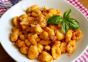 Gnocchi di patate con ragù di carne alla bolognese e decorati con alcune foglie di basilico.