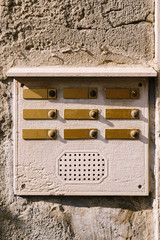 Close-ups of building facades in Venice, Italy. An old vintage intercom and a mailbox on a stone wall. On door where placed this old rusty doorbells.