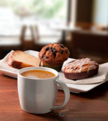 Café con leche con  bizcocho, magdalena  sobre tabla de madera, desayuno. White coffee with sponge...