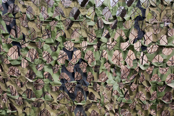 Military camouflage net on the fence