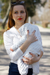 Young beautiful mom with little baby in her arms on the street. Happy family.