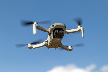 Small drone in flight on blue sky background