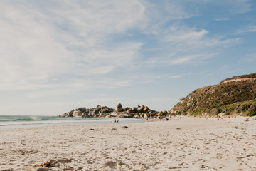 A few locals enjoy swimming and surfing in Cape Town's pristine  Llandudno beach at sunset.