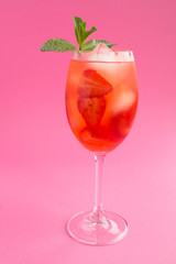 Cocktail drink with strawberry and ice in a glass on the pink  background. Location vertical. Closeup.