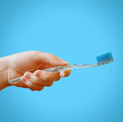 Female hand holds a blue toothbrush