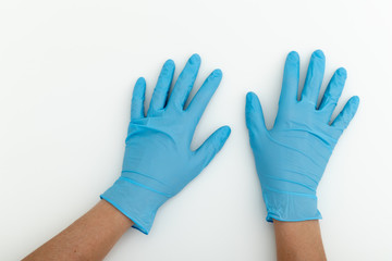 Hands in blue latex gloves on white table