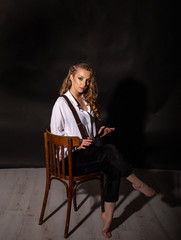 vertical portrait of a cute barefoot blonde sitting on a chair in the studio