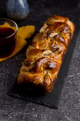 close up roll with poppy seeds with tea on dark concrete