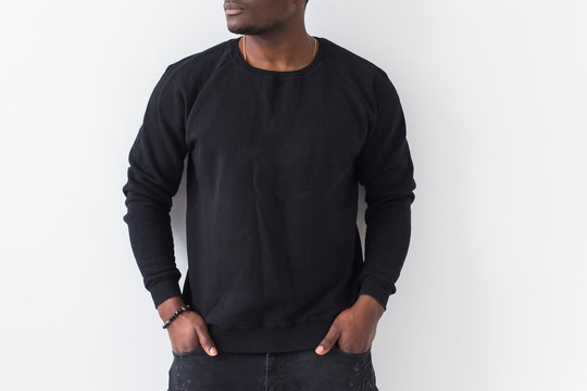 Close-up of n African American man posing in black sweatshirt on a white background. Youth street fashion photo with afro hairstyle.