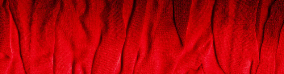 Bright red texture of binding crumpled fabric. Red textile background with natural folds. Close-up