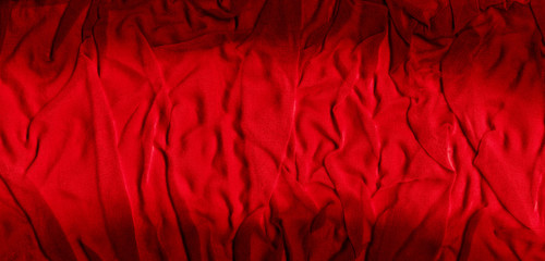 Bright red texture of binding crumpled fabric. Red textile background with natural folds. Close-up