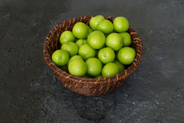 Fresh green plums in the wicker basket.