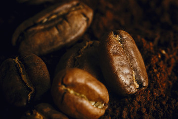  Fresh aromatic roasted coffee beans macro view. Coffee beans close up on grounded coffee pile. Space for text. Brown tone moody image