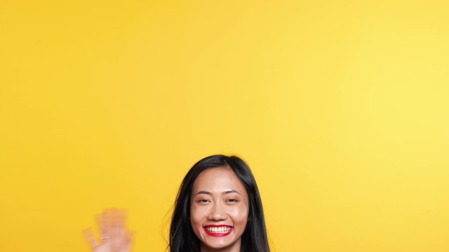 Asian woman waving hello or goodbye to camera and slowly disappear down