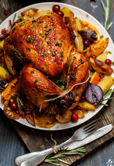 Roast whole chicken with roast vegetables on plate on a table