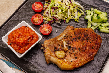 Grilled pork steak. Cole slow salad, tomato sauce, fresh vegetables