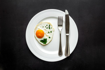 Fried eggs on plate - black kitchen table top-down