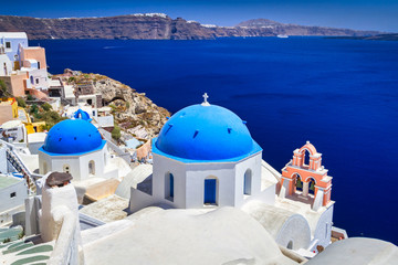 Naklejka premium Niebieskie kopuły kościoła i białe domy w pięknym mieście Oia na wyspie Santorini, Grecja.
