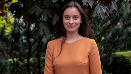 Close-up portrait of beautiful caucasian woman in orange dress.