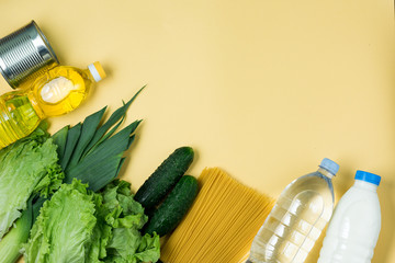 Essential fresh products lie on a yellow background. Greens food. Food delivery covid-19 epidemic, Donation. Top view. Copy space.