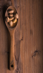 
A wooden spoon and some pistachios on a wooden background. Vertical format. Aerial view.
