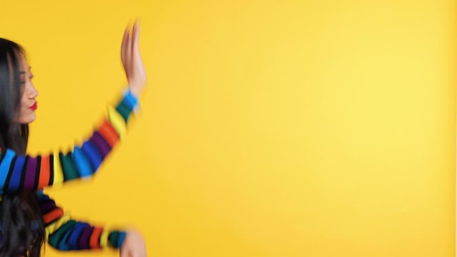 Asian woman funny dancing on yellow background